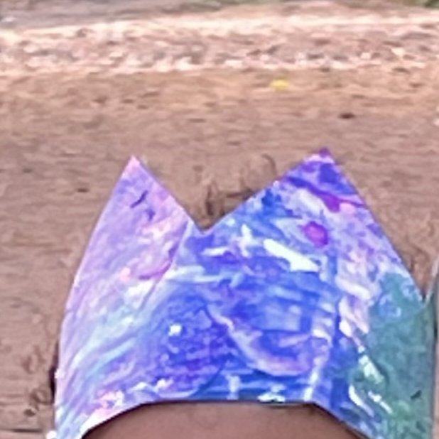 A child wearing a purple and blue painted crown made from the class canvas