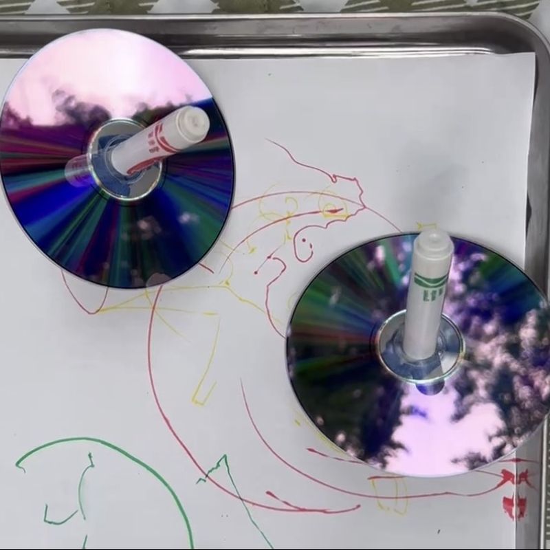 Spinning tops made from discs and markers drawing loops on paper