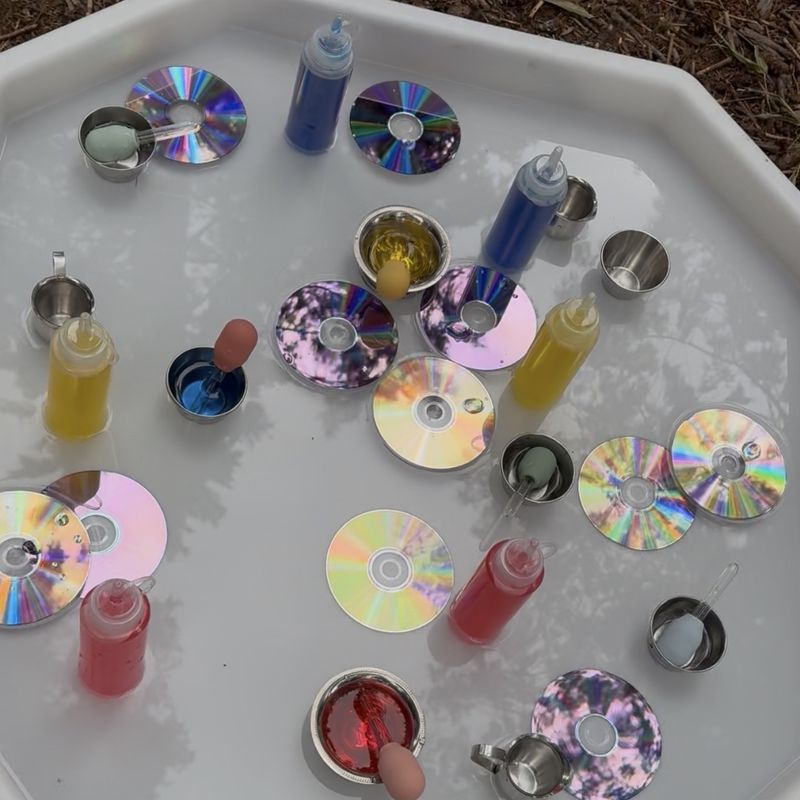 A water tray with droppers, squeeze bottles of colored water, small cups, and shiny discs